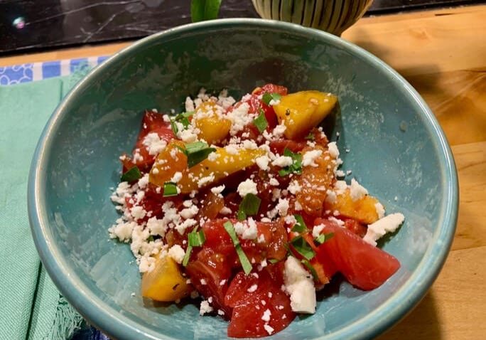 A bowl of food with tomatoes and feta cheese.