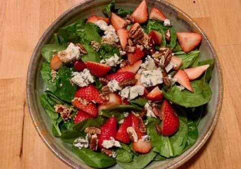 Spinach salad with strawberries, pecans, and cheese.