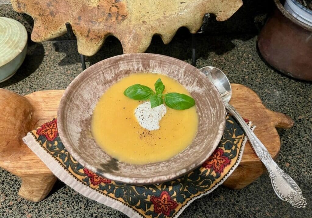 A bowl of soup with cream and basil leaves.