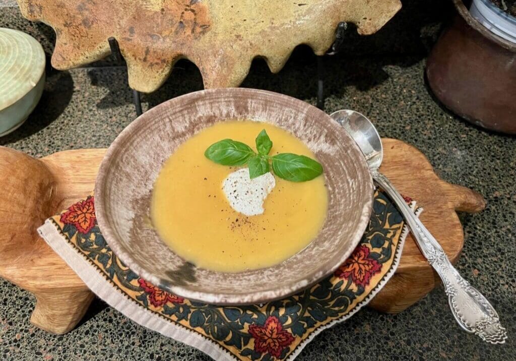 Creamy soup with basil in bowl.