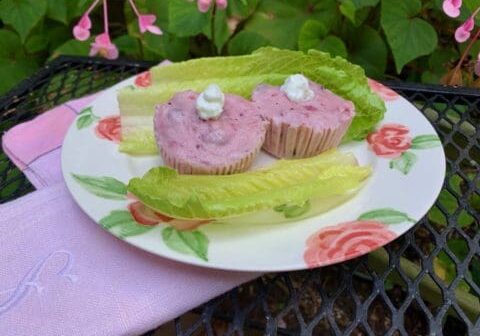 Two pink and white dessert cups on a plate