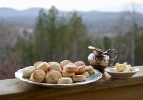 Biscuits on a plate with butter and a creamer.