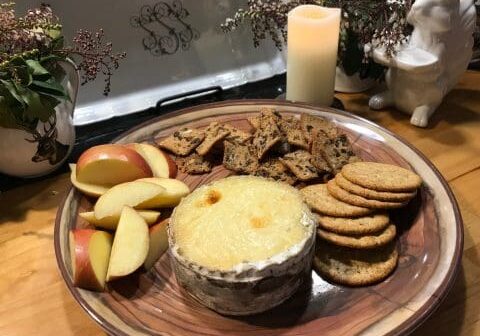 Cheese, crackers, apples on a wooden plate.