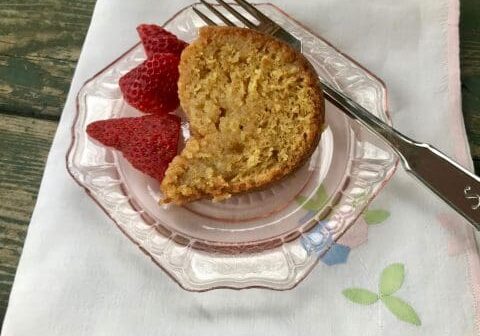 Slice of cake on a pink plate with strawberries.