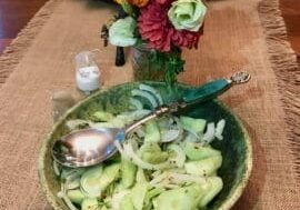 A bowl of cucumber salad on a table.