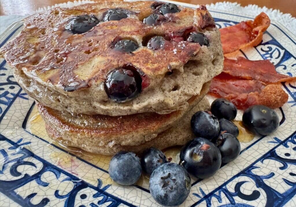 Blueberry pancakes with bacon on a plate.