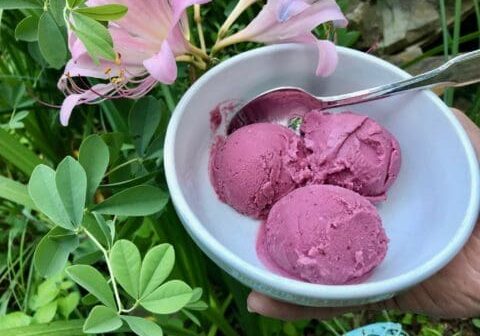 Three scoops of purple ice cream in a bowl.