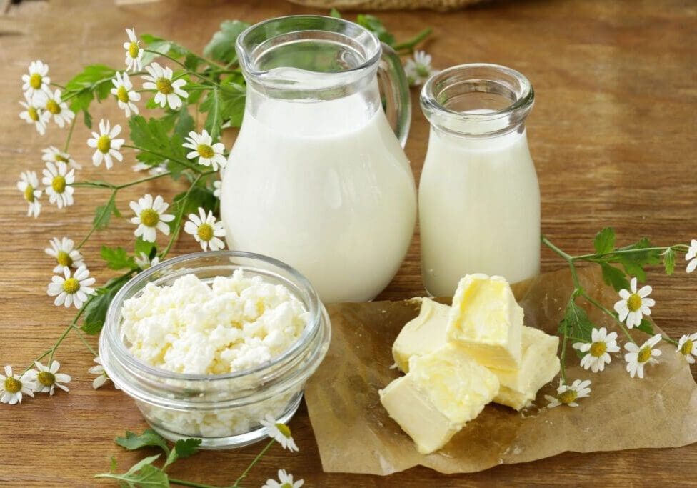 A table topped with milk and butter next to flowers.