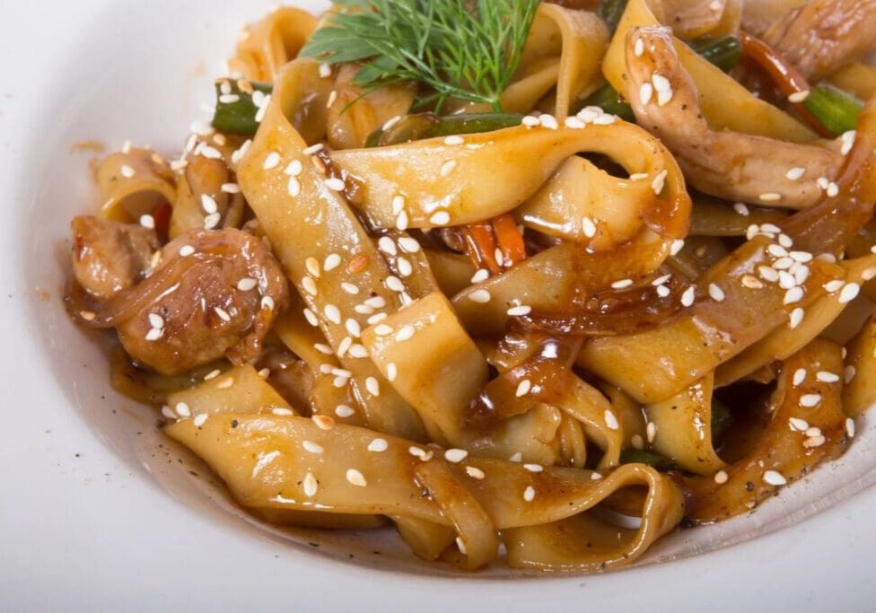 A close up of noodles with meat and sesame seeds