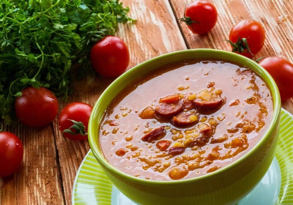 A bowl of soup with tomatoes and parsley.