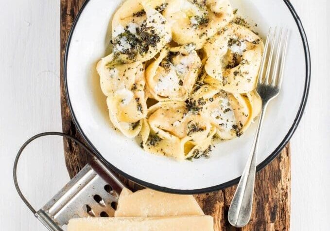 A bowl of pasta with cheese on top.