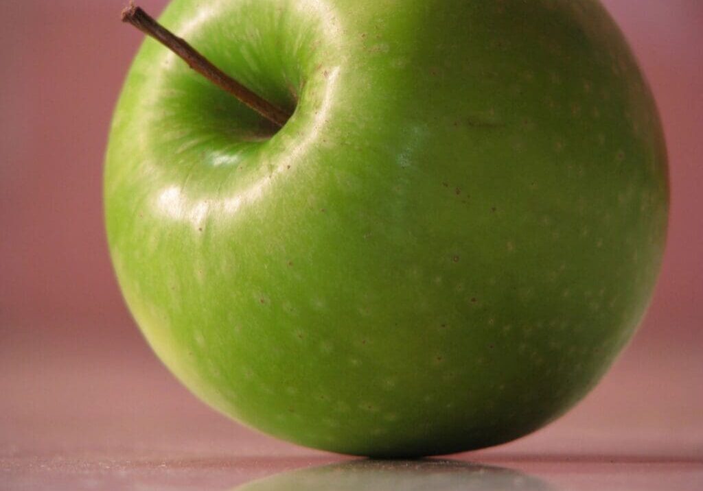 A green apple sitting on top of a table.