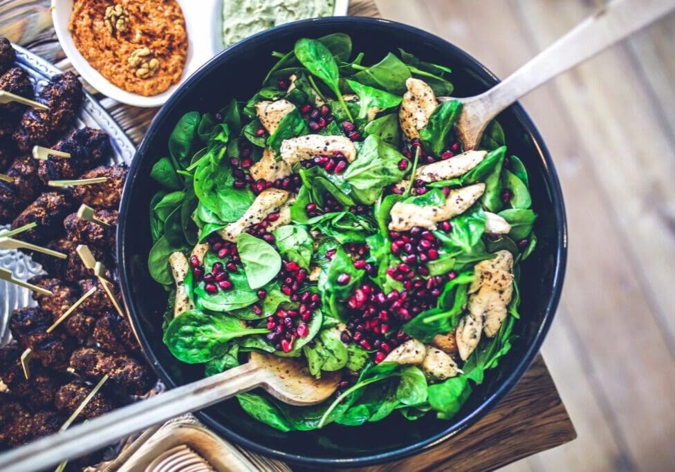 A bowl of salad with two forks in it.