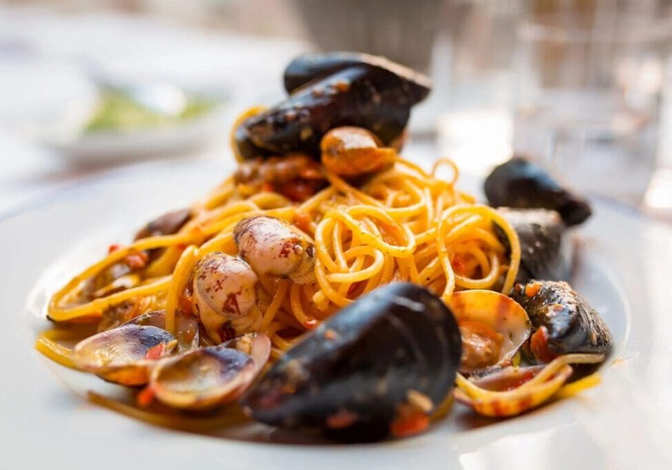 A plate of pasta with mussels and sauce.