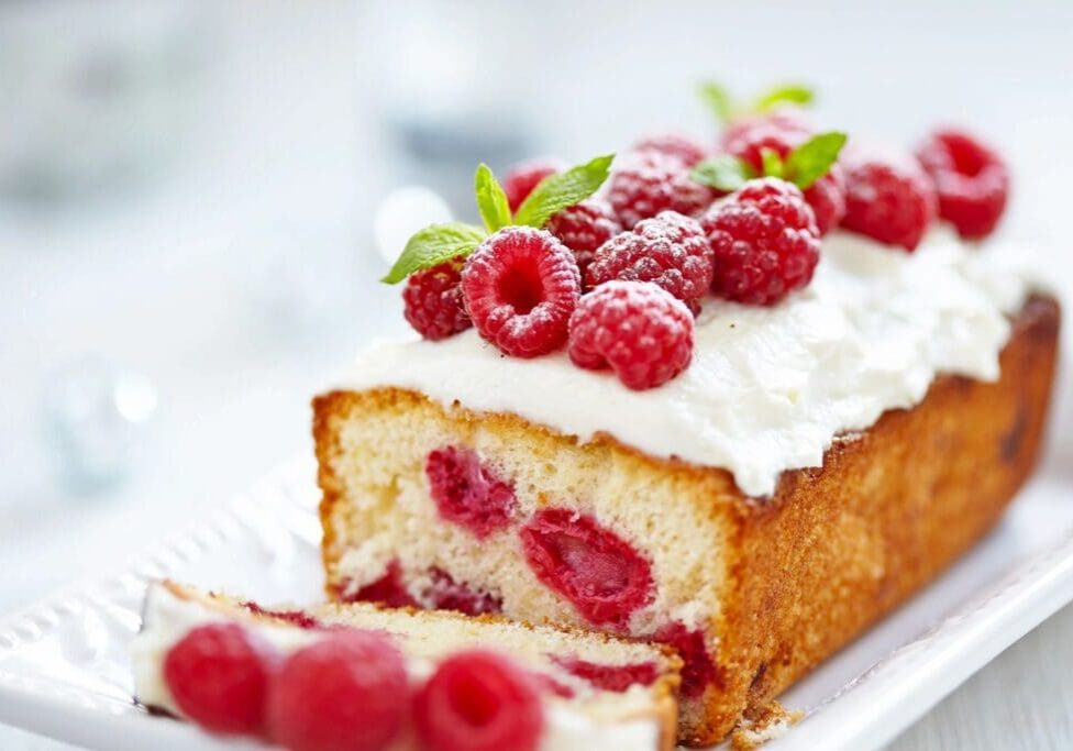 A piece of cake with raspberries on top.