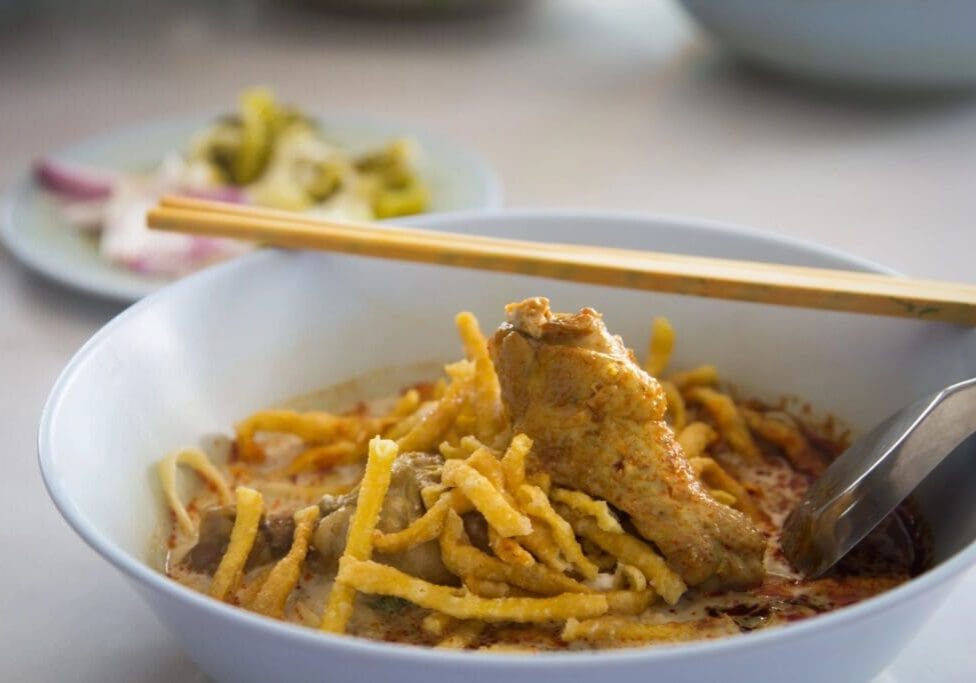 A bowl of food with noodles and meat.