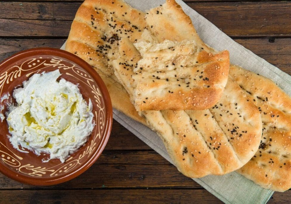 A bowl of yogurt and some bread on the table