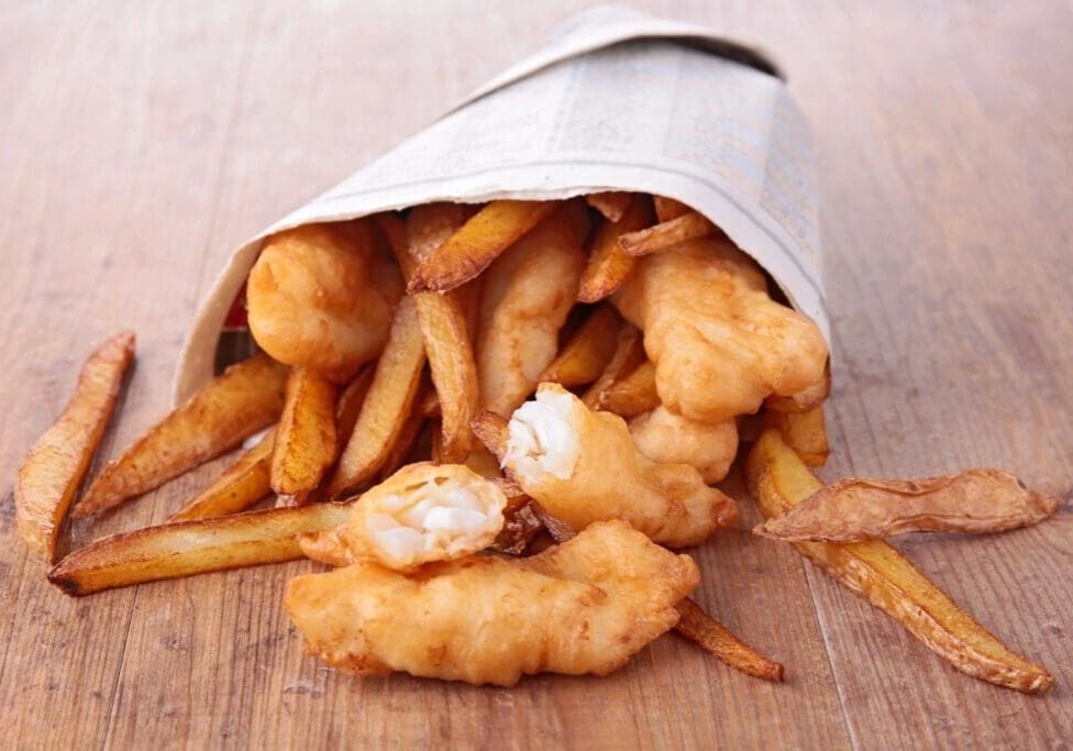 A paper bag filled with fish and chips.