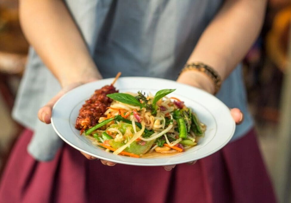 A person holding a plate of food on top of their lap.