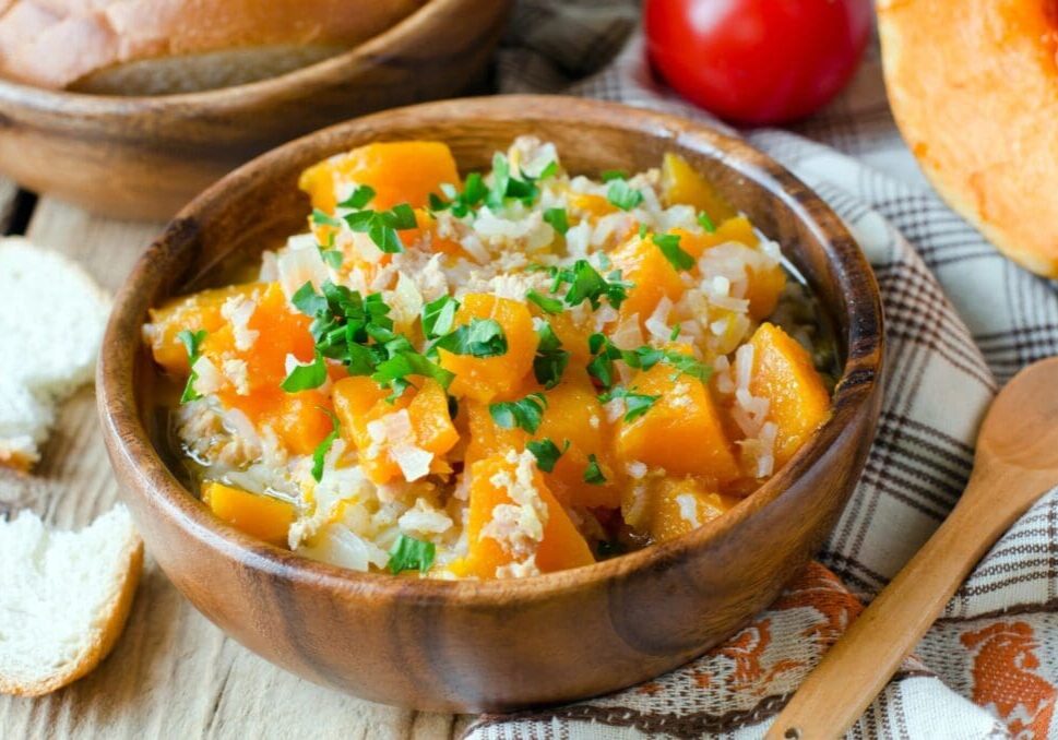 A bowl of rice and squash on the table.