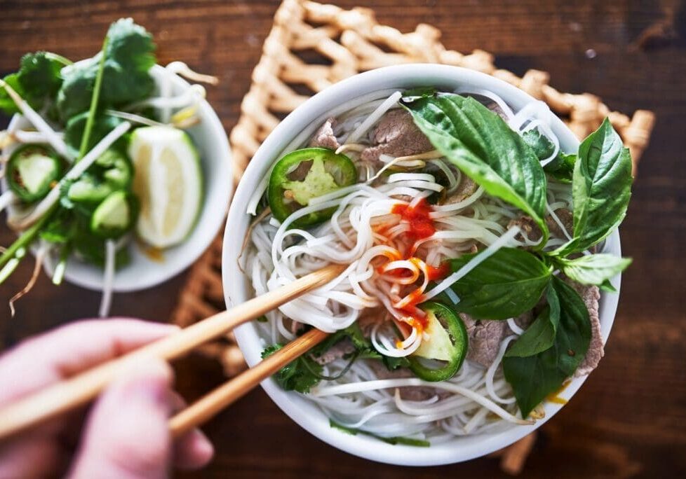 A bowl of soup with chopsticks in it.