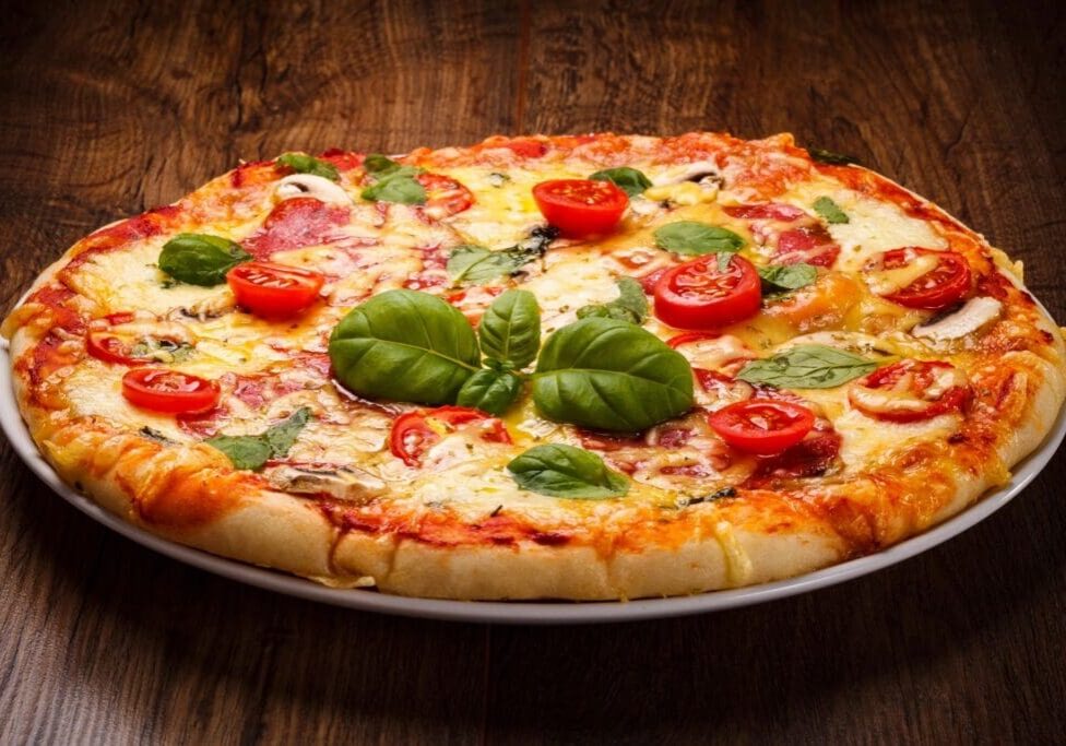 A pizza with tomatoes and basil on it.