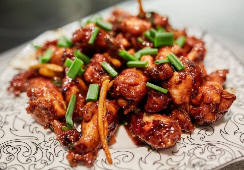 A plate of food with meat and green onions.