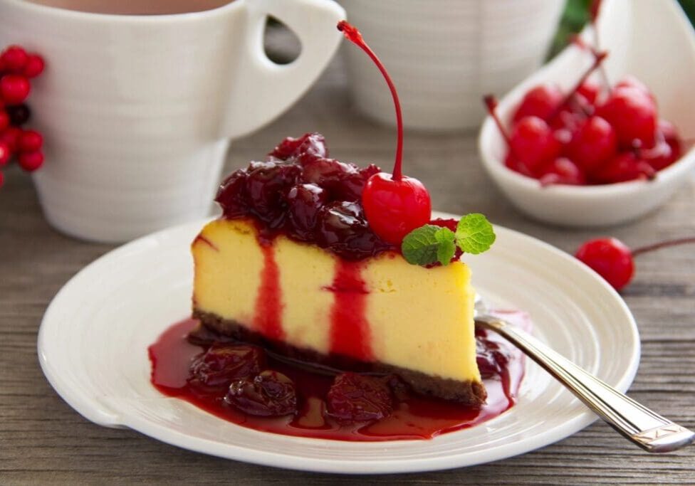 A piece of cheesecake with cherries on top.