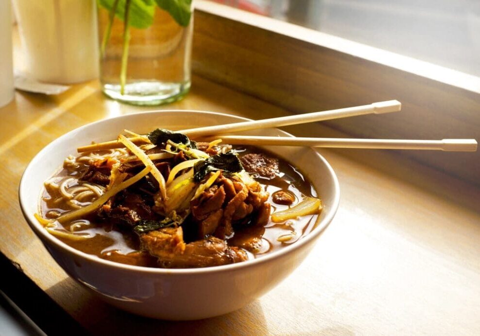 A bowl of soup with meat and noodles.