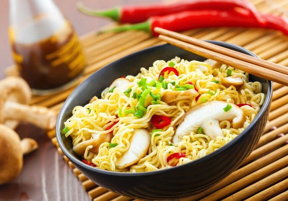 A bowl of noodles with mushrooms and peppers.