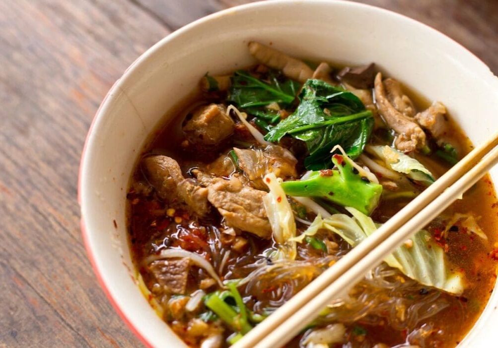 A bowl of food with meat and vegetables.