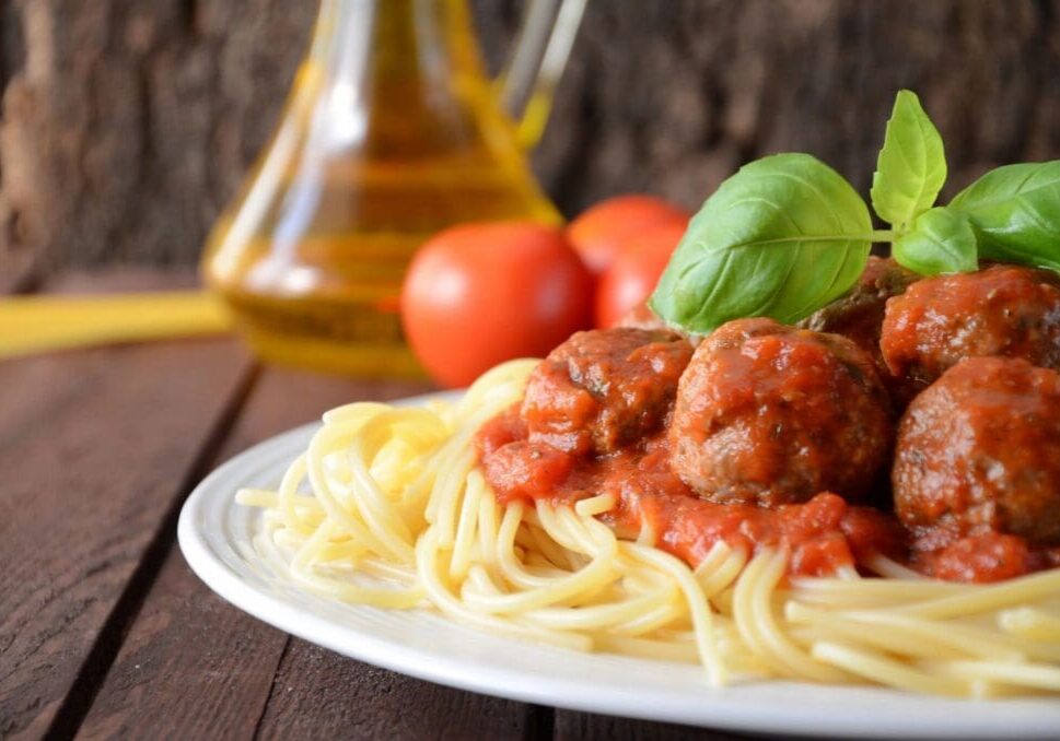 A plate of spaghetti and meatballs on top of a table.