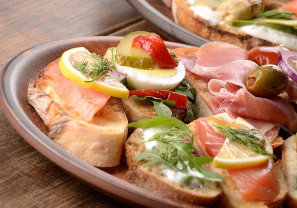 A plate of food with bread, ham and vegetables.