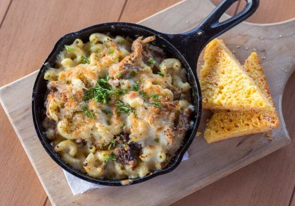 A pan of macaroni and cheese with some bread on the side.