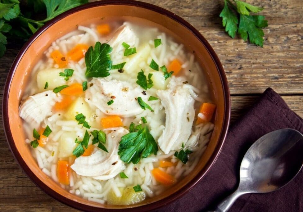 A bowl of soup with carrots and rice.