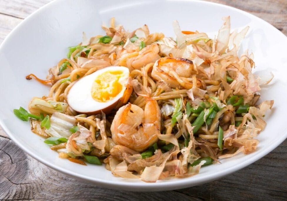 A bowl of food with shrimp and egg on top.