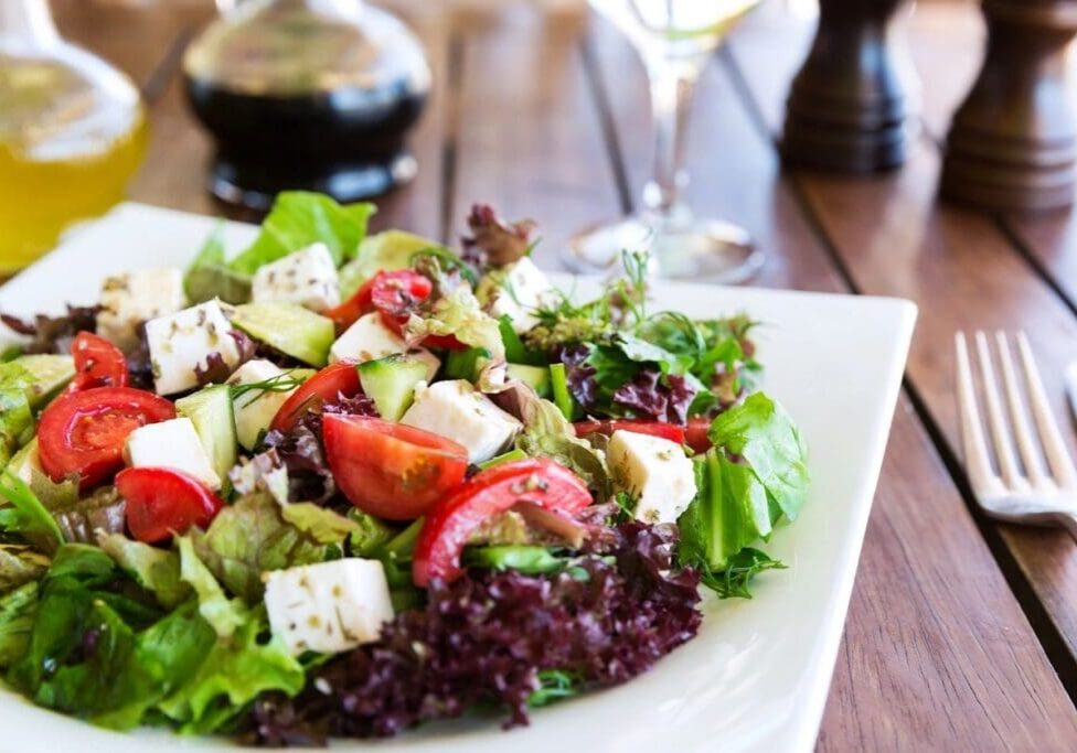 A salad with feta cheese and tomatoes on top of it.