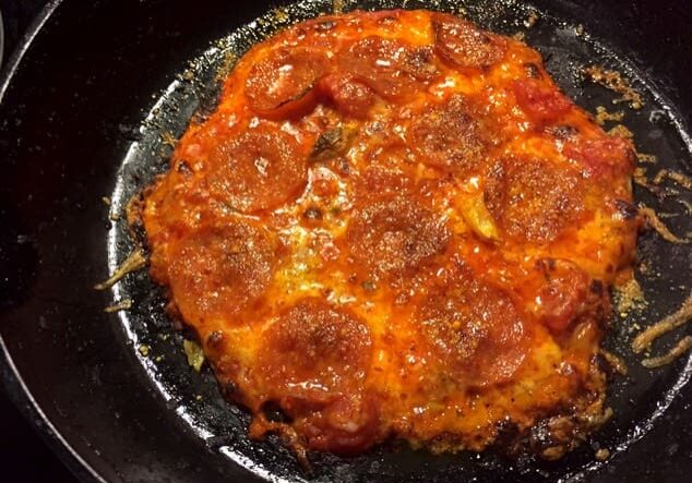 A pizza sitting on top of a pan covered in sauce.