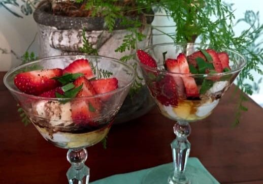 Two glasses with fruit in them on a table.