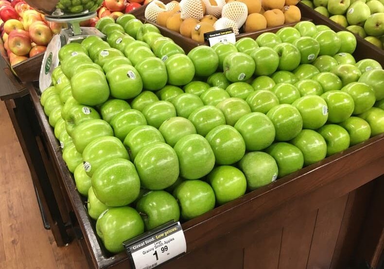 A display of green apples in a store.