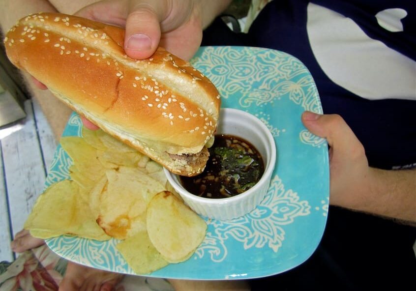 A person holding a sandwich on top of a plate.