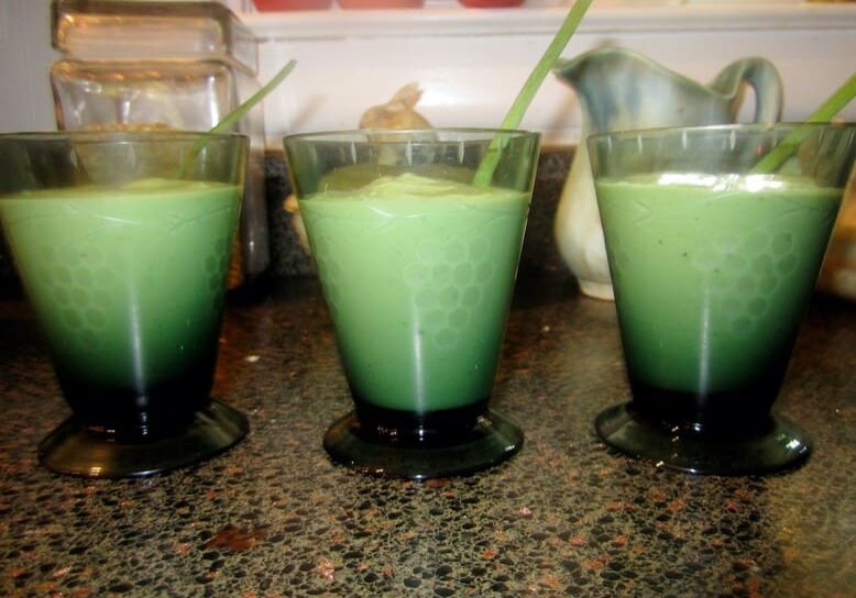 Three glasses of green smoothie on a table.