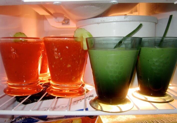 A refrigerator with several glasses of juice and lime.