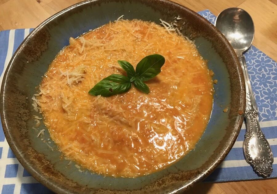 A bowl of soup with basil leaves on top.