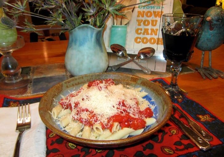 A bowl of pasta with sauce and cheese on the table.