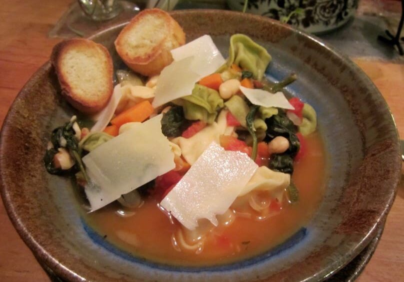 A bowl of soup with bread on the side.