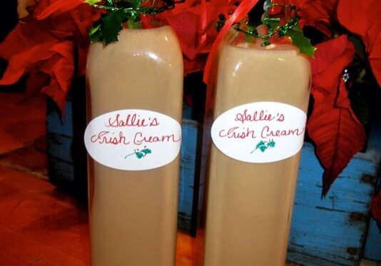 Two bottles of liquid with poinsettia plants in them.