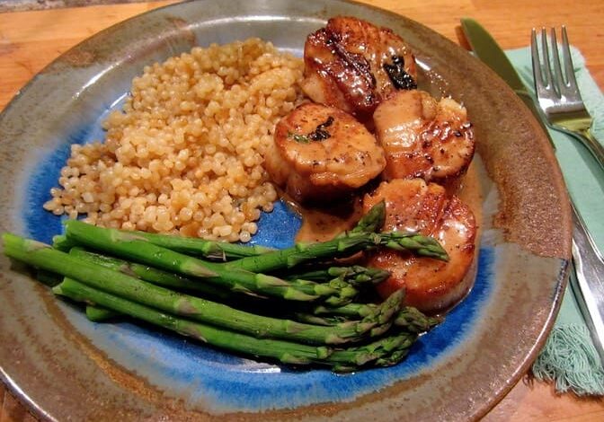 A plate of food with asparagus, rice and meat.