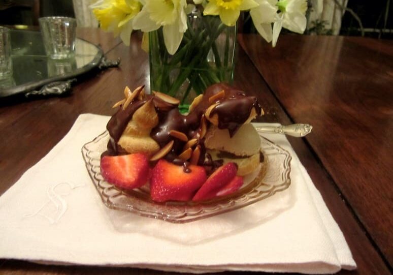 A bowl of fruit on the table with flowers