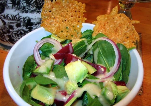 A bowl of salad with crackers on the side.